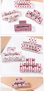 Detailed views of red plaid and polka dot heart patterns on acetate hair claw clips