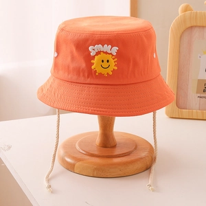 Détail d'un chapeau bob orange en toile avec broderie smile et cordon de serrage blanc