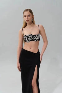 Detailed view of black two-piece evening set featuring a crystal rose on the top and slit skirt