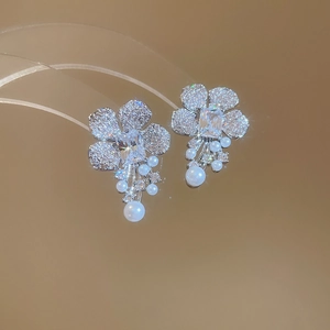 Close-up of zircon flower earrings with long pearl tassels and shimmering silver finish