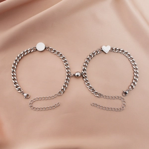 Close-up of magnetic heart and round pendants on silver cuban link bracelets for couples