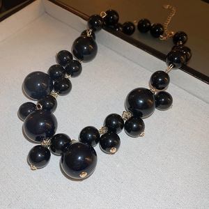 Detail of high-gloss black irregular pearl necklace with gold-toned metal clasp links