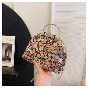Close-up of floral embroidery detail on vintage shell bag with gold chain strap