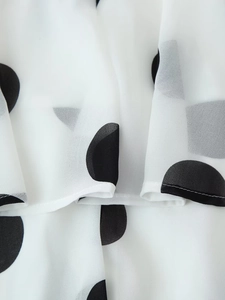 Detaillierte Makroansicht von weißem Chiffonstoff mit großen schwarzen Punkten und Saumstichen