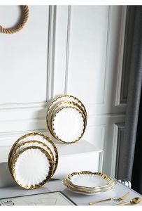 Detail of white ceramic dinner plate with gold rippled rim and luxury glossy finish