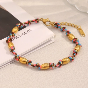 Détail macro du bracelet en cordon tressé avec perles dorées 18K et fermoir mousqueton