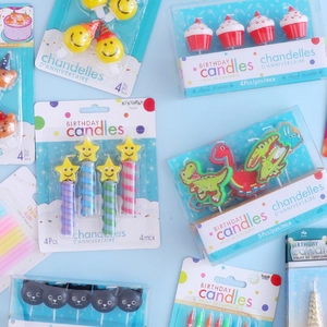 Various cute cartoon birthday candles including smiley faces and dinosaurs on blue background