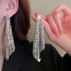 Detail of silver tassel earrings with delicate metal mesh texture and geometric triangles