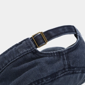 Close-up of adjustable metal buckle and washed denim fabric on navy flat top cap