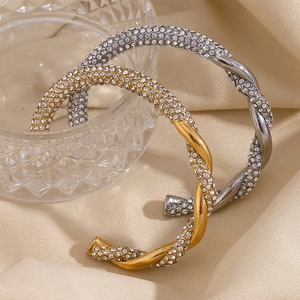Nahaufnahme von gedrehten Armreifen mit vollem Diamantbesatz in Gold und Silber