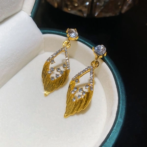 Dettaglio degli orecchini dorati a forma di foglia con zirconi in una scatola regalo