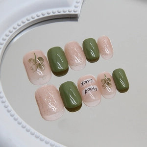 Short square press-on nails in avocado green and pink with clover and Good Luck motifs