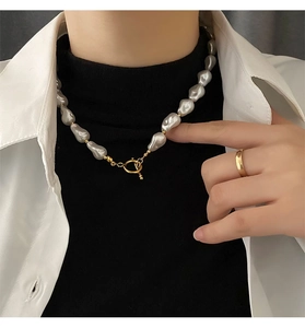 Close-up of baroque pearl necklace with silver metallic luster and golden OT toggle clasp