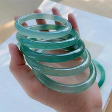 Close-up of translucent green agate chalcedony bangles held by hand for quality detail