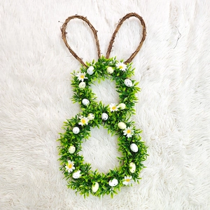 Close-up of Easter rabbit wreath with green leaves, white daisies and colorful eggs