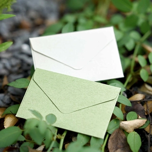 Mini vintage textured paper envelopes in white and light green on natural leaves