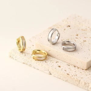 Macro shot of gold and silver S925 earrings with mother of pearl on stone base