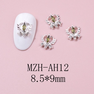 Macro detail of winged heart nail charms with green marquise zircon and silver base