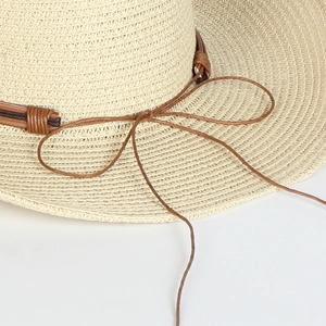 Detailed close-up of woven straw texture and brown decorative rope knot on a sun hat