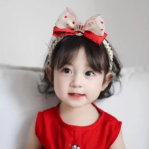 Red and white polka dot baby headband with a large bow and gold crown on a child model