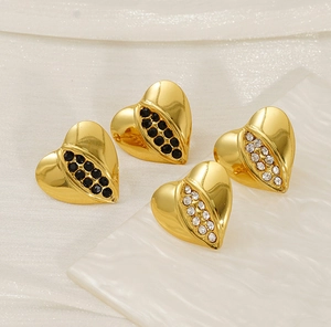 Detail view of 18K gold heart earrings with black and white rhinestones set on a white base