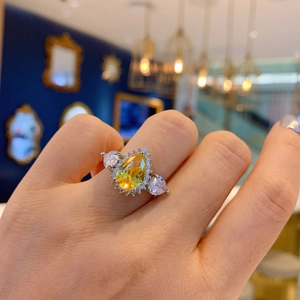 Detail of pear-cut yellow gemstone ring with side diamonds on model's hand