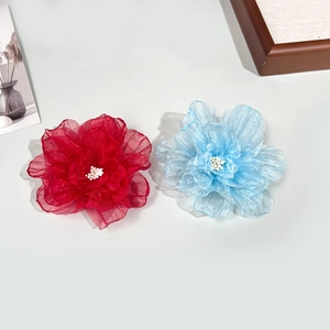 Détail de pinces à fleurs en organza rouge et bleu clair avec paillettes et perles