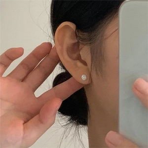 Close-up of minimalist S925 sterling silver smiling face stud earring on ear lobe