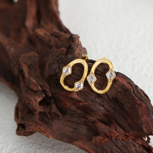 Elegant gold oval hoop earrings featuring rhomboid zircon stones on a rustic wood background