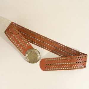 Detail eines braunen Boho-Gürtels aus PU-Leder mit Metallösen und Nietenverzierung