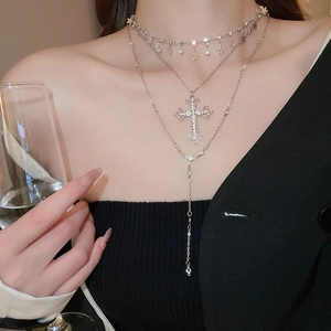 Macro detail of layered silver necklace with cross and star pendants on a model neck
