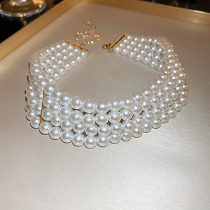 Close-up of a four-layer pearl necklace with elegant gold clasp on a silk tray