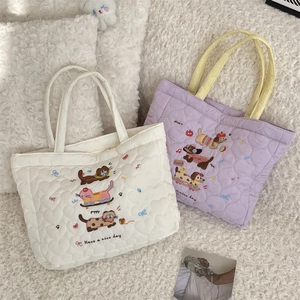 Détail de texture matelassée en cœur et broderie chiot sur sacs cabas doux