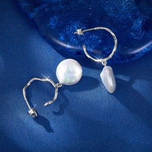 Macro shot of S925 silver C-shape earrings featuring large iridescent baroque pearls