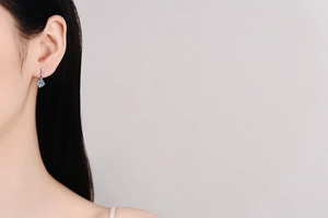 Close-up of a silver drop earring featuring a blue gemstone on a female model