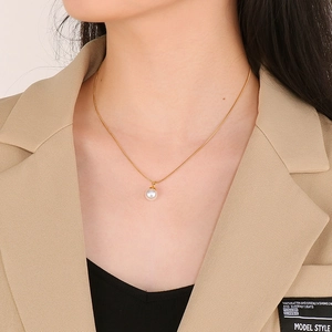 Elegante collana in acciaio al titanio dorato con ciondolo a perla bianca su modella