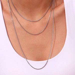 Detailed close-up of a silver-tone multi-layered minimalist fine chain necklace on model