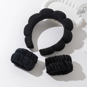 Close-up of black sponge cloud headband set with matching wristbands on a white decor base