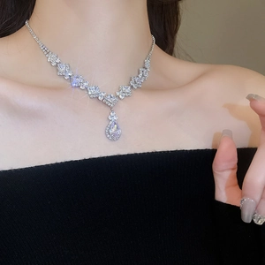 Close-up of silver necklace featuring rhombus and water drop zircon pendant on a model