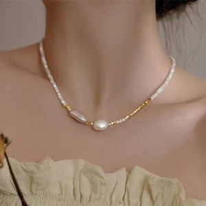 Close-up of Baroque freshwater pearl necklace with gold cube beads on female model