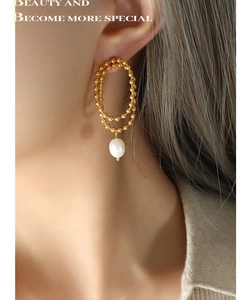 Detail of double-layered gold bead hoops with baroque pearl pendants on model
