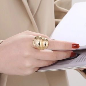 Close-up of a chunky 18k gold plated stainless steel ring on model holding magazine
