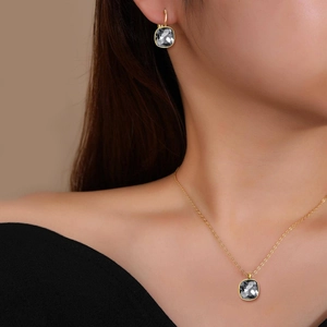 Model wearing a gold stainless steel jewelry set with square grey zircon pendant and earrings