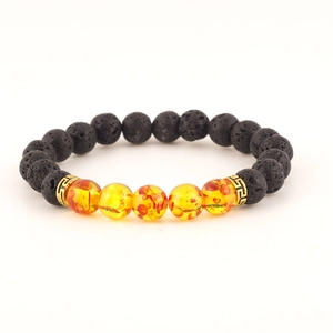 Detailed close-up of black lava stone and amber bead bracelet featuring gold spacers.
