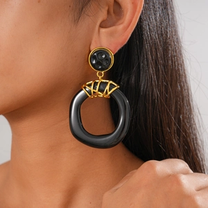 Close-up of model wearing chunky resin earrings in contrasting black and gold colors