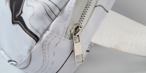 Detailed close-up of marble pattern fabric with premium silver metal zipper and white strap