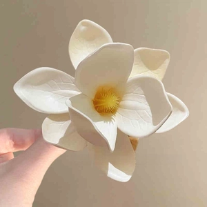 Close-up of matte cream flower hair clip with yellow pistil and realistic petal texture