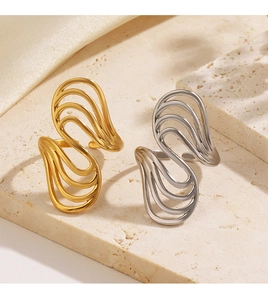 Macro detail of wave-shaped hollow rings in gold and silver finish on stone surface