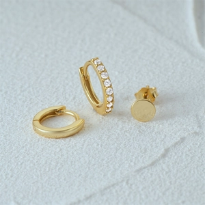 Macro detail of gold-plated earring set featuring triple diamond accents and studs