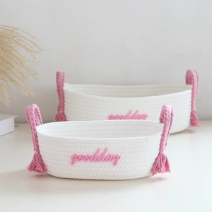 Close-up of white cotton rope storage baskets with pink handles and goodday embroidery